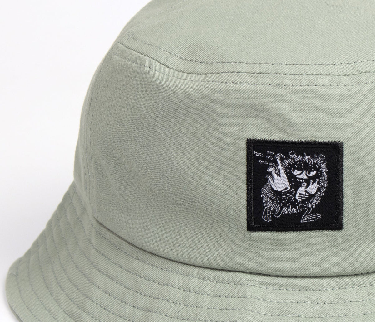 6. Close-up of Moomin Stinky Bucket Hat in light green, highlighting embroidered patch