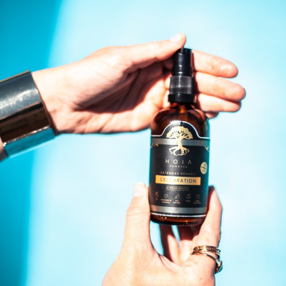 2. HOIA homespa Shimmering Body Oil in hand against blue background, highlighting bottle design