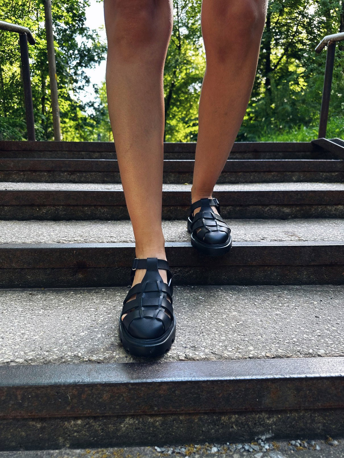 2. Women's black Samelin sandals on stairs, showcasing rugged sole and woven design
