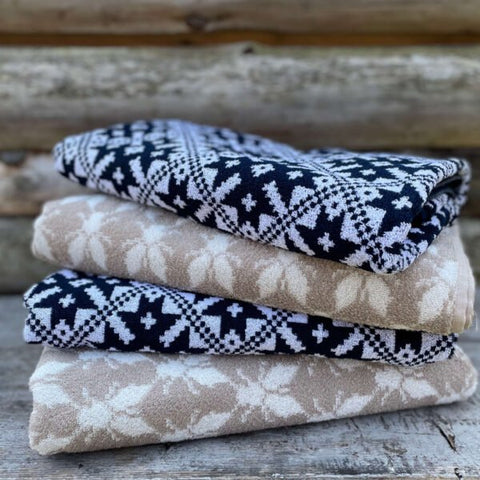 2. Stack of three sauna towels in navy and beige with traditional patterns on wooden surface