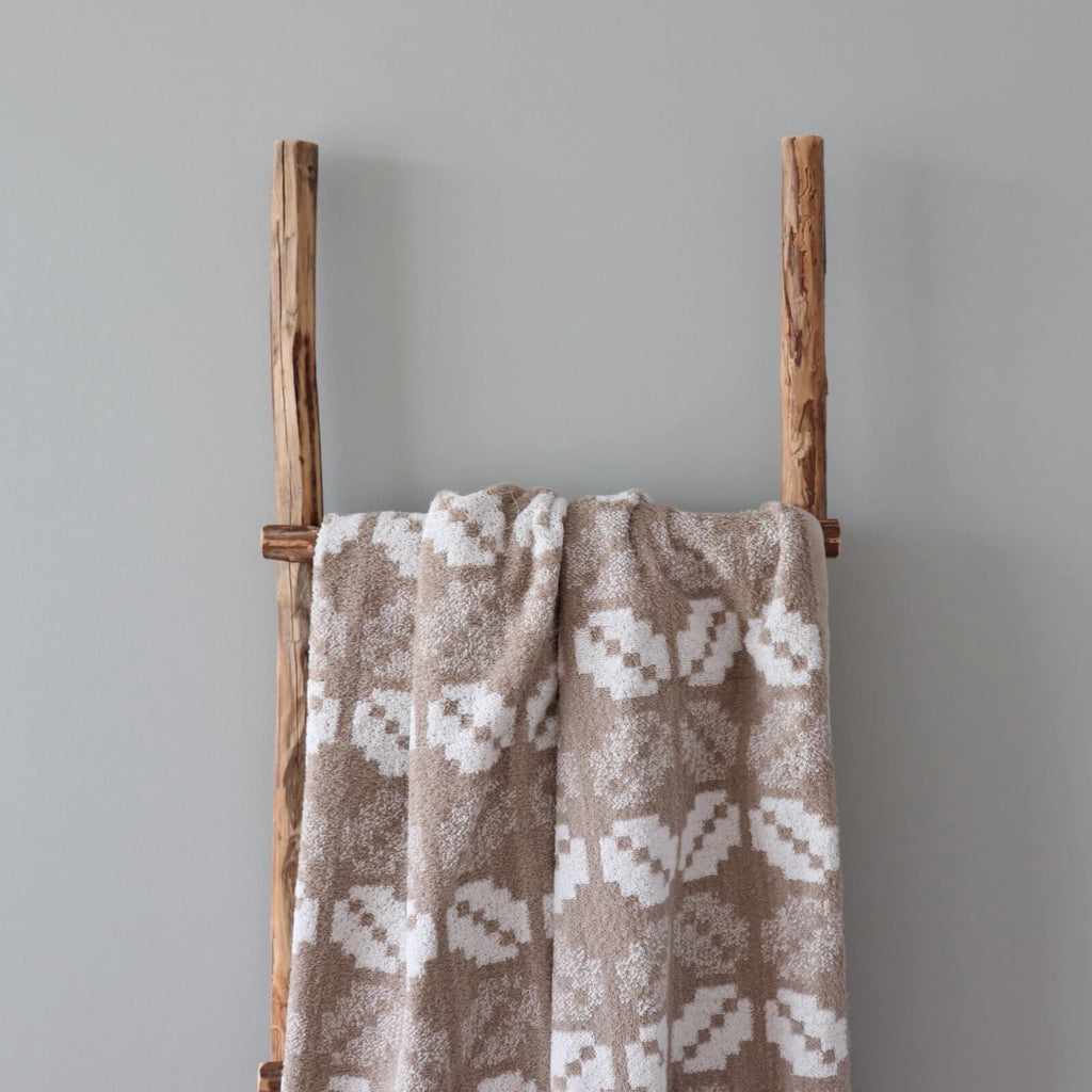 1. Beige and white terry sauna towel with Lääne County mitten pattern draped over a wooden ladder against a grey wall
