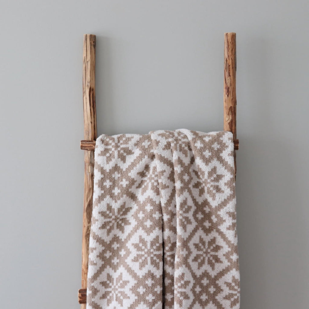 2. Beige and white terry sauna towel with Viljandi County mitten pattern hanging on wooden ladder against grey background