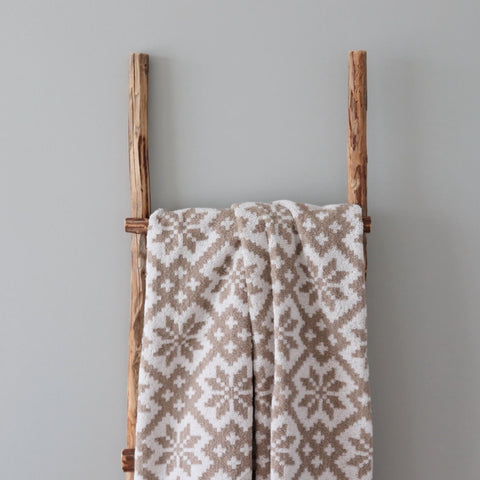 2. Beige and white terry sauna towel with Viljandi County mitten pattern hanging on wooden ladder against grey background