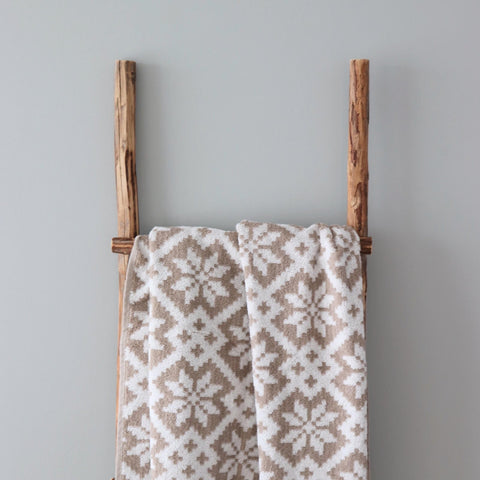 1. Beige and white terry sauna towel with Viljandi County mitten pattern draped over wooden ladder against light grey wall