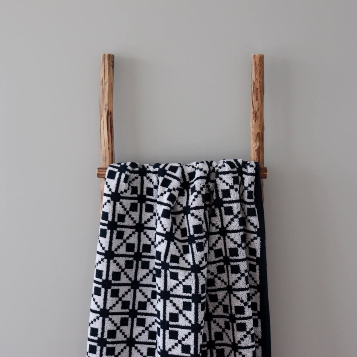 2. Black and white cotton sauna towel featuring Virumaa mitten design hanging on rustic wooden ladder