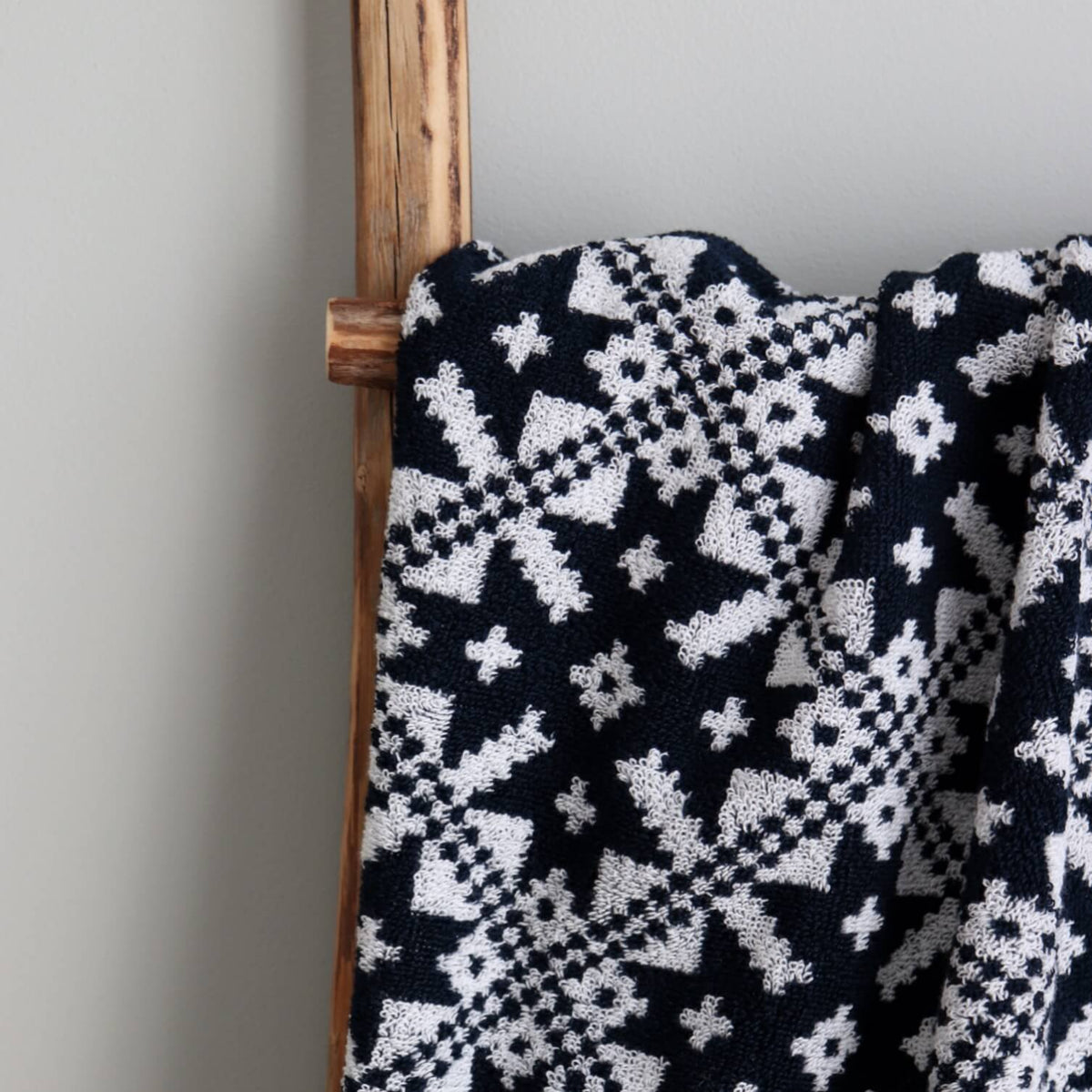 3. Close-up of navy sauna towel with white Pärnumaa mitten pattern on wooden ladder