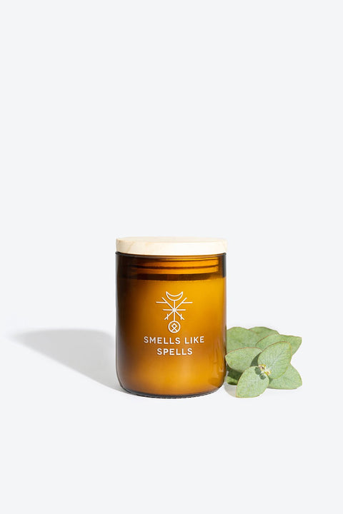 1. Smells Like Spells Scented Candle NORNS in amber glass jar with lid, featuring brand logo and eucalyptus leaves