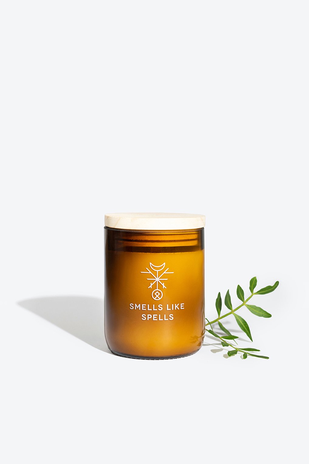 2. Smells Like Spells FREYA candle in amber glass jar with wooden lid, styled with greenery, studio setting
