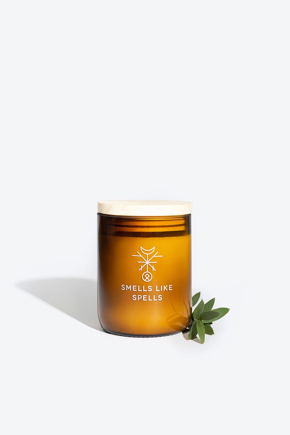 2. Smells Like Spells Scented Candle ODIN in amber glass jar with wooden lid, featuring green leaves, handcrafted with soy wax and essential oils