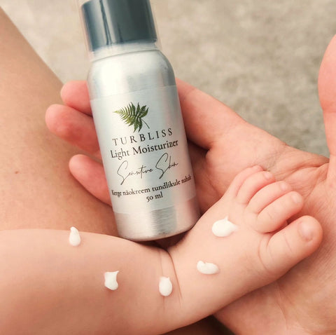 2. Turbliss Matte Face Cream 50ml held in hand, with cream applied on baby's arm