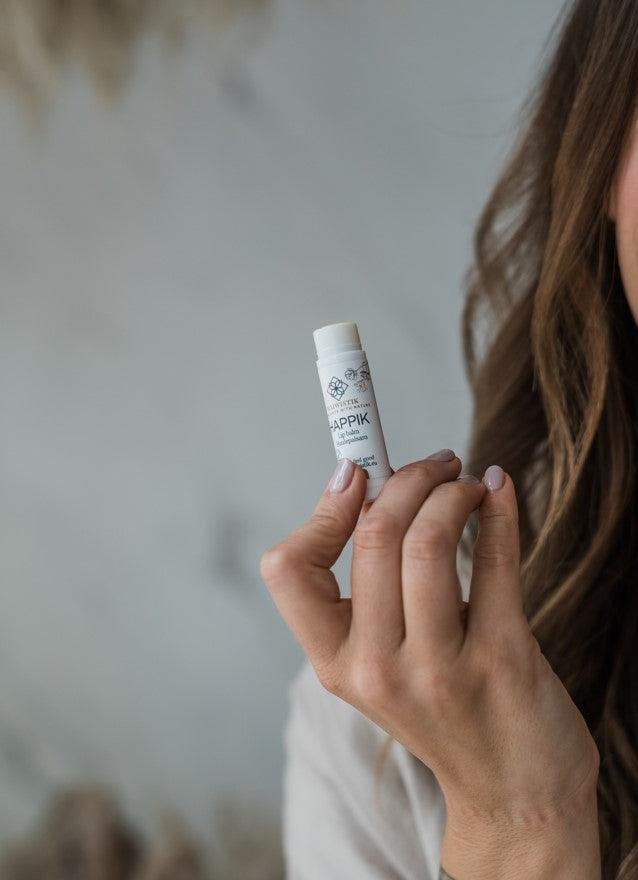 1. Woman holding MaiWistik Happik Lip Balm, showcasing natural and handmade Estonian product