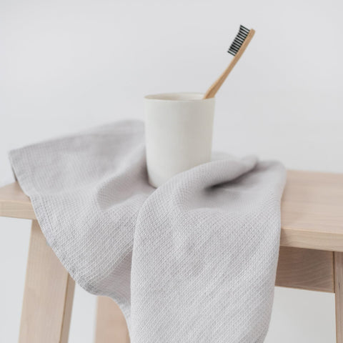 2. Silver linen fine waffle towel draped over wooden stool with toothbrush in cup, simple bathroom decor