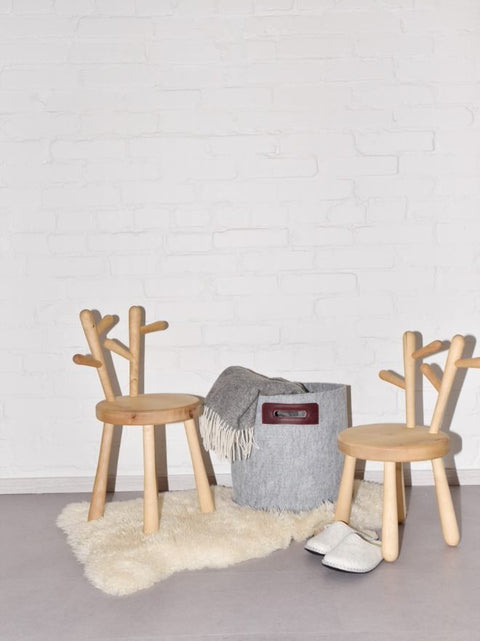 1. Lifestyle image of grey and bordeaux Felt Omaking Basket in a cozy room setting with wooden chairs and a rug