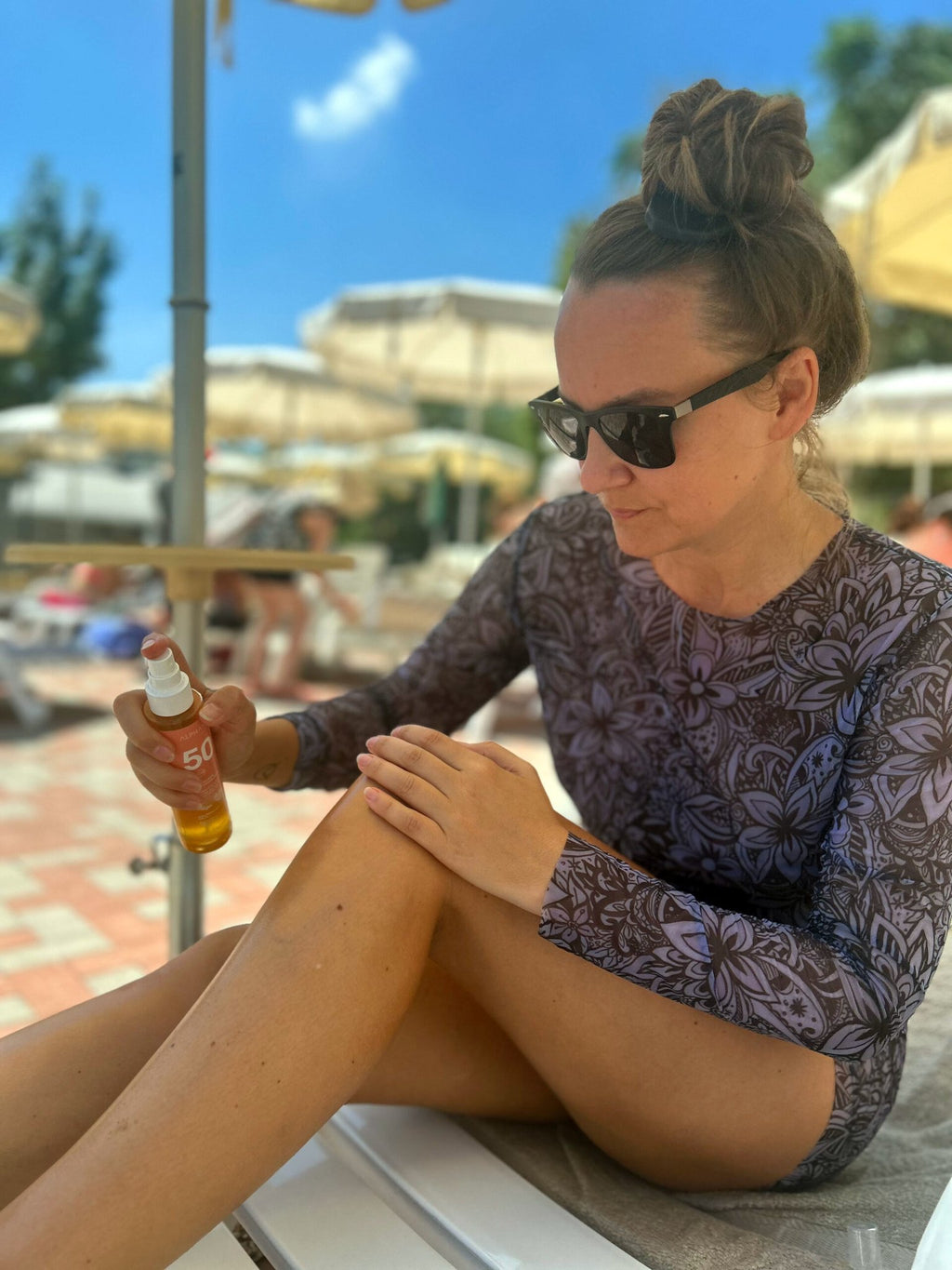 2. Woman applying sunscreen while wearing Smarttan's tan-through mini leggings and matching top at the beach