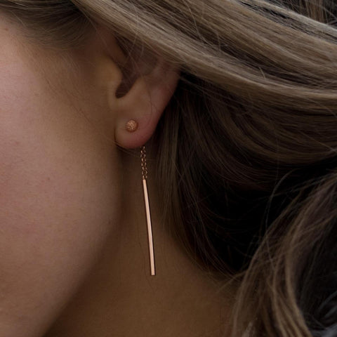 1. Close-up of woman wearing MyaMoon Stardust Falling Earrings in rose gold, showcasing long drop design