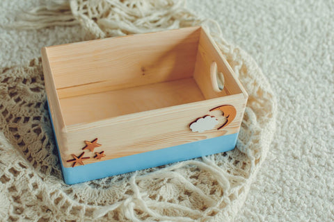 2. Light blue handmade wooden storage box with cut-out heart designs, featuring golden stars and cloud decorations, placed on a textured fabric background, ideal for storing small items.