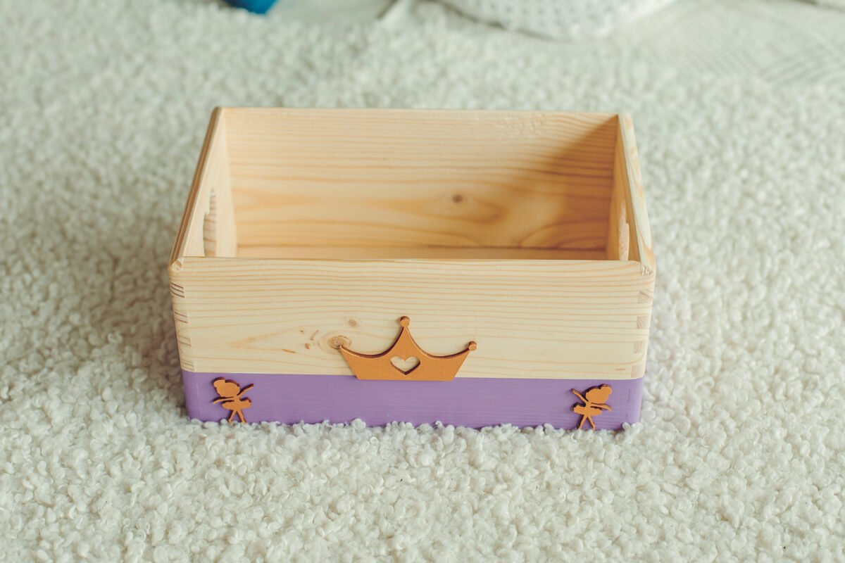 2. Lilac wooden storage box with golden crown and fairy decorations on a textured white surface, ideal for storing small items, by Kai aš mažas buvau