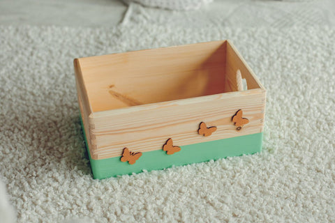 2. Mint wooden storage box with cut-out heart designs and golden butterfly decorations, placed on a textured white surface, ideal for storing small items, by Kai aš mažas buvau
