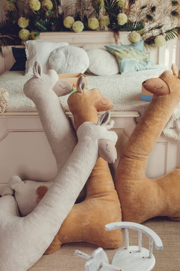 4. Group of rust and beige alpaca plush toys leaning against bed in decorated room