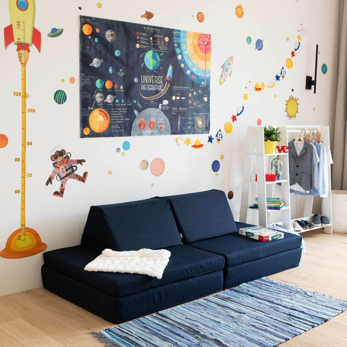1. Navy blue activity play mattress set arranged as a sofa in a children's room with space-themed wall decor