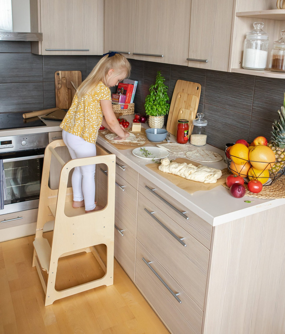 6. Child in yellow top using natural wood Montessori helper tower step stool in kitchen