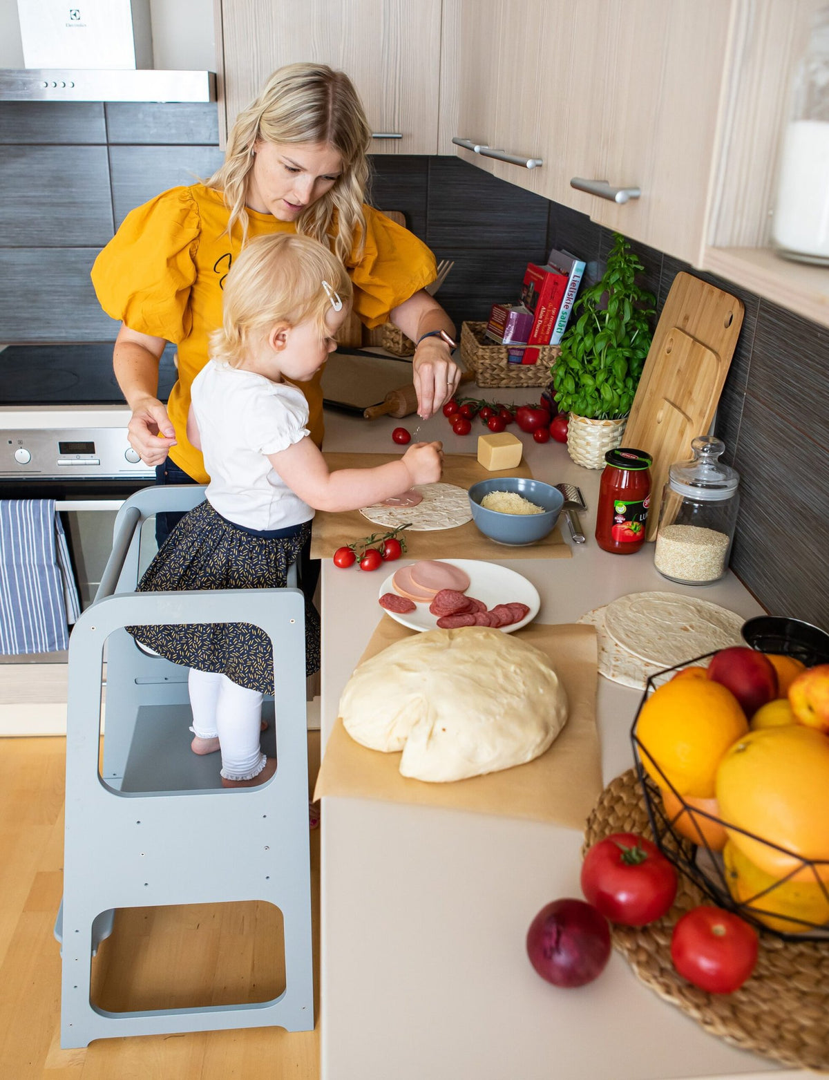 10. Woman and child using blue Montessori helper tower step stool in kitchen