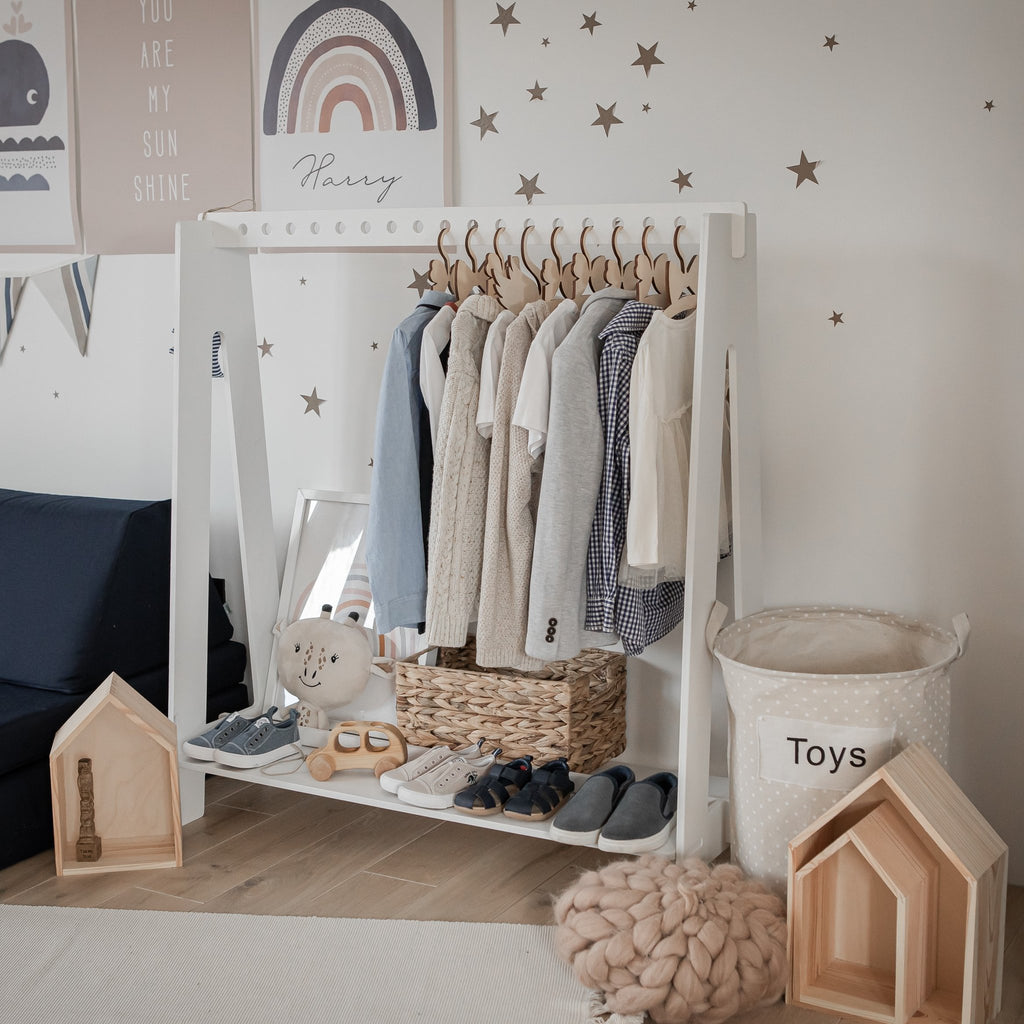 5. White toddler clothing rack with neutral-toned clothes and toys in a star-themed children's room