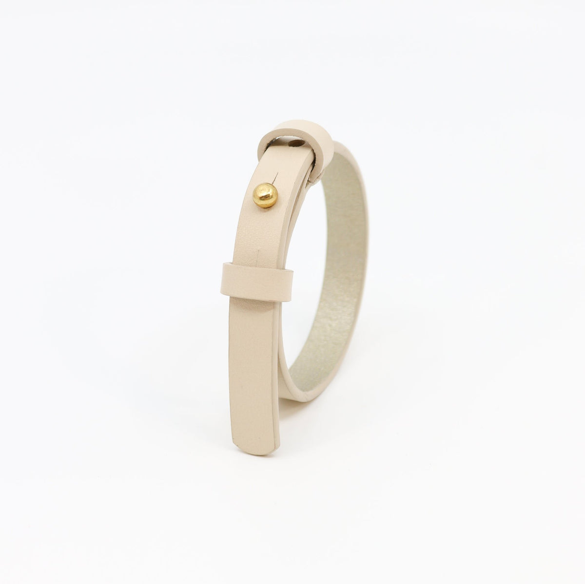 3. Studio shot of Tairi Roosve ivory leather bracelet with brass fastener, highlighting adjustable design