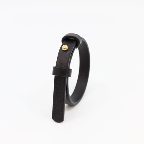 1. Black leather bracelet with brass fastener by Tairi Roosve, shown in studio setting
