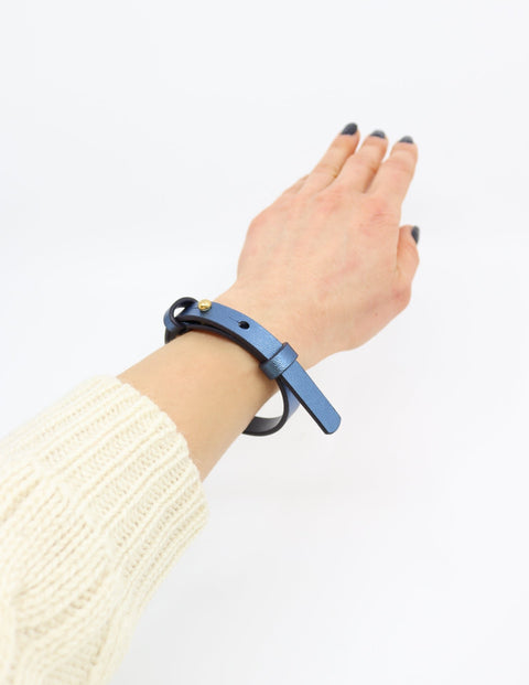 3. Metallic blue leather bracelet by Tairi Roosve worn on a wrist, showcasing adjustable fit and brass fastener