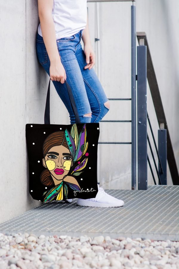 1. Woman holding Garbanota HANDBAG LILY - COLORED with artistic print, standing against a modern backdrop