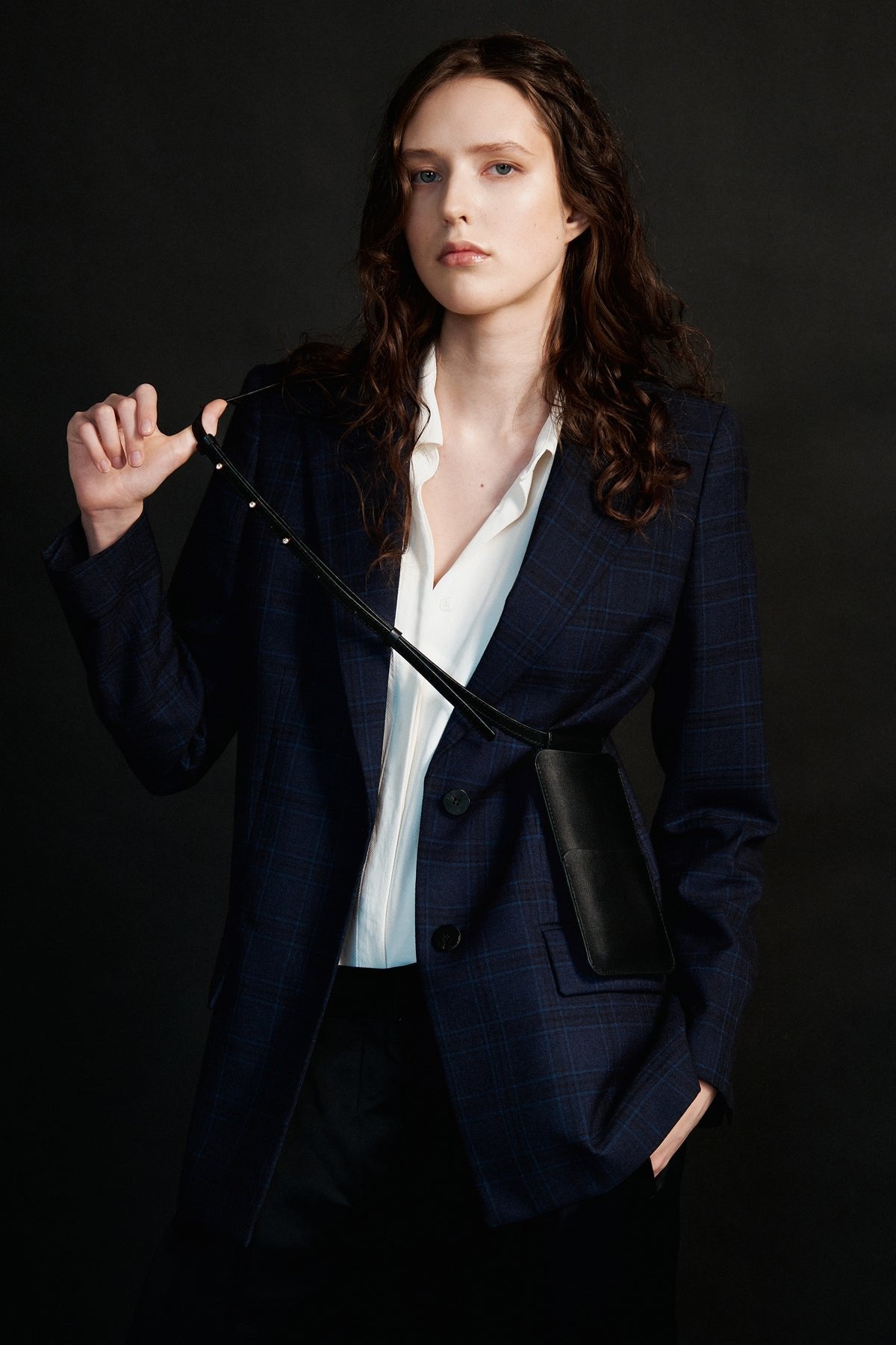 2. Women's black leather phone bag by Tairi Roosve shown crossbody with a navy blazer, highlighting adjustable strap