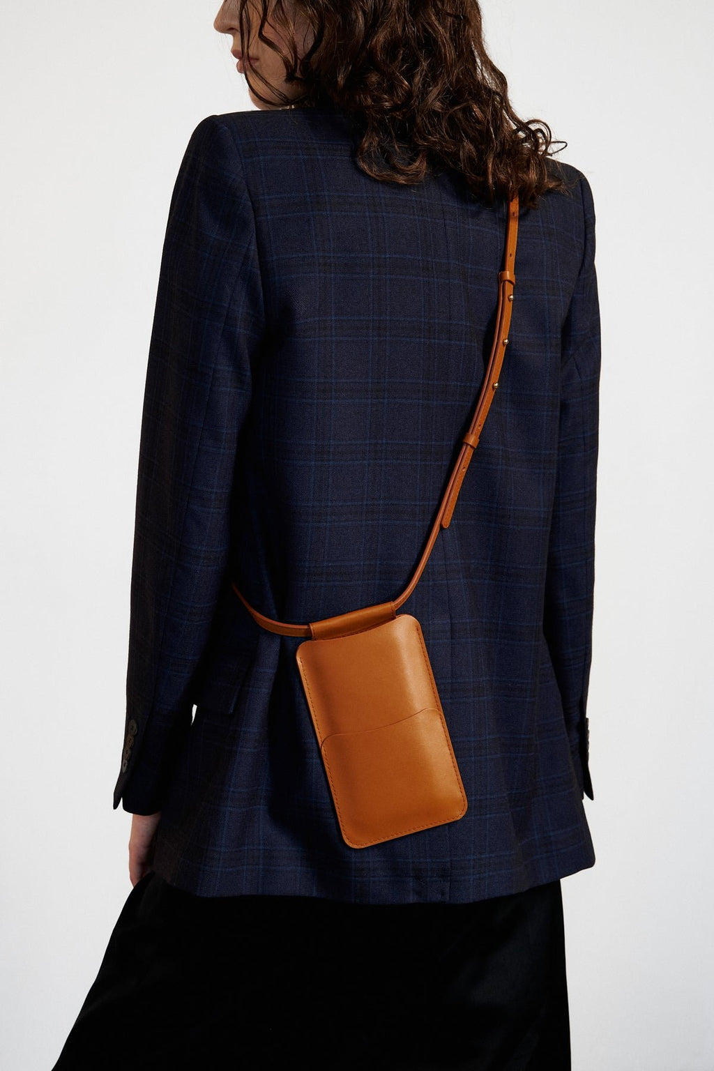 3. Woman posing with Tairi Roosve tan leather phone bag, highlighting crossbody design and card slots