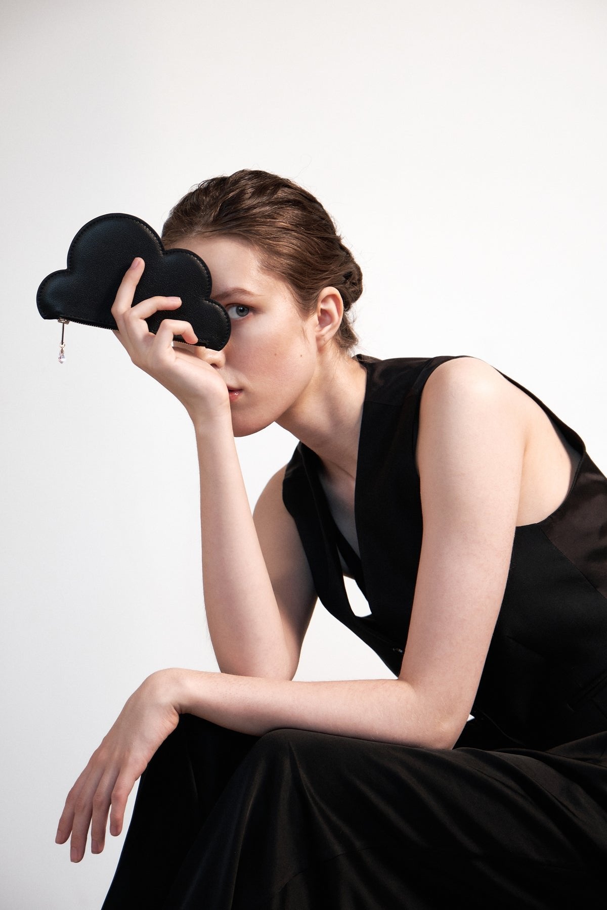 2. Woman posing with Tairi Roosve black Leather Cloud Purse, showcasing unique design and elegance