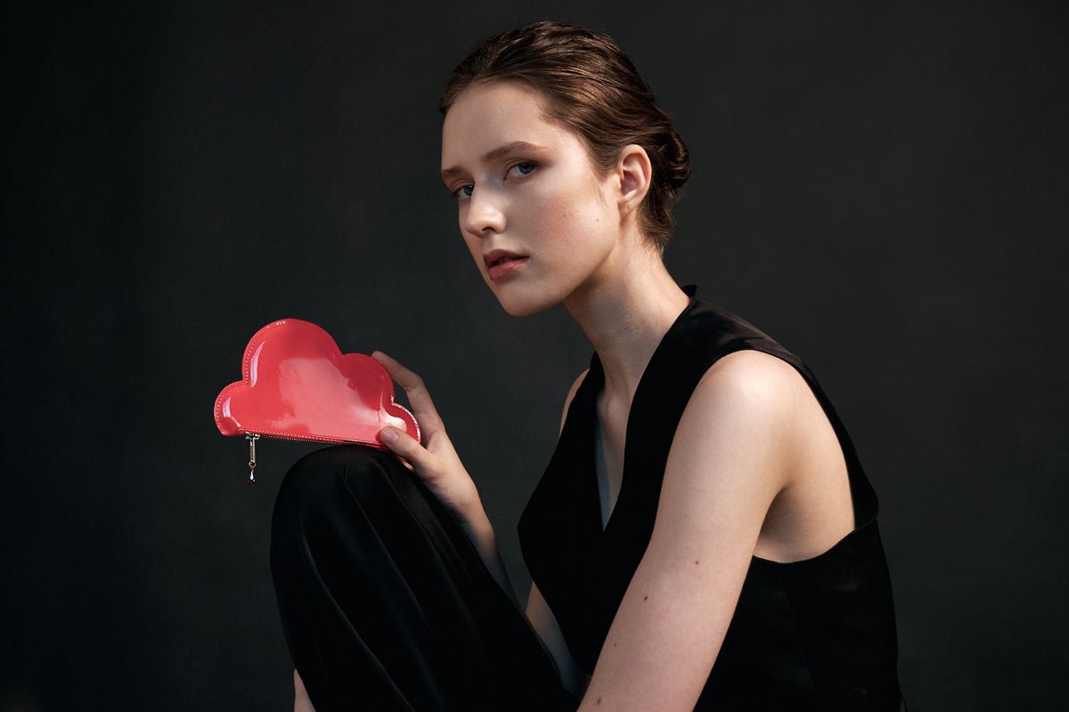 1. Woman holding Tairi Roosve pink leather cloud purse with Swarovski crystal zip in studio setting