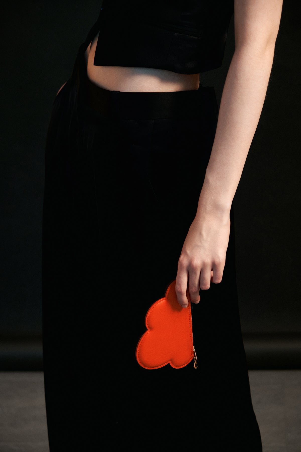 1. Woman holding Tairi Roosve orange Leather Cloud Purse, showcasing chic design and Swarovski crystal zip in lifestyle setting