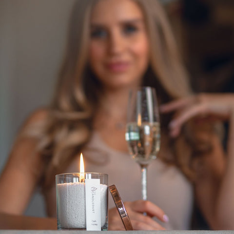 1. Woman holding a glass of champagne with a lit Candledust Mango Lime powdered candle in the foreground