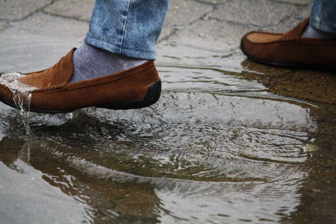 1. Brown leather shoes repelling water in a puddle, demonstrating GoGoNano EcoProtect waterproofing spray effectiveness