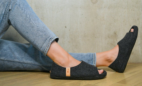 1. Women's TOKU Bern Slippers in dark gray lambswool, worn with jeans, showcasing open-toe design and comfort