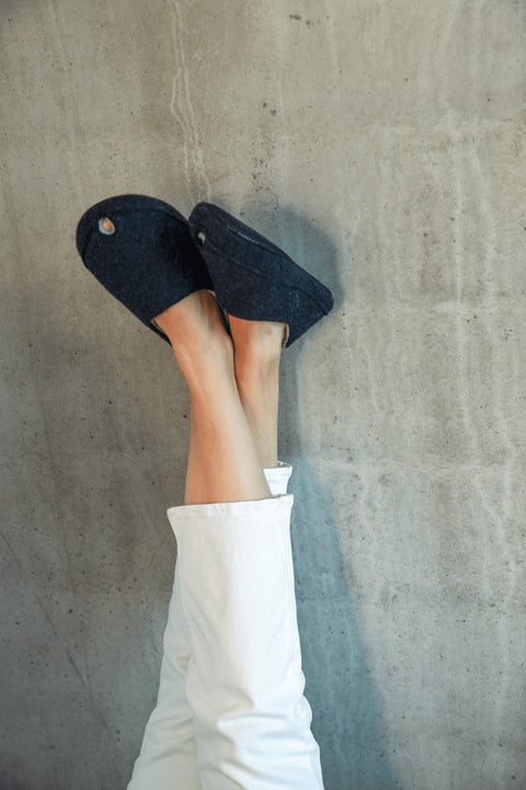 2. Unisex dark grey TOKU Budapest slippers worn by model with legs up against a wall, highlighting comfort and style