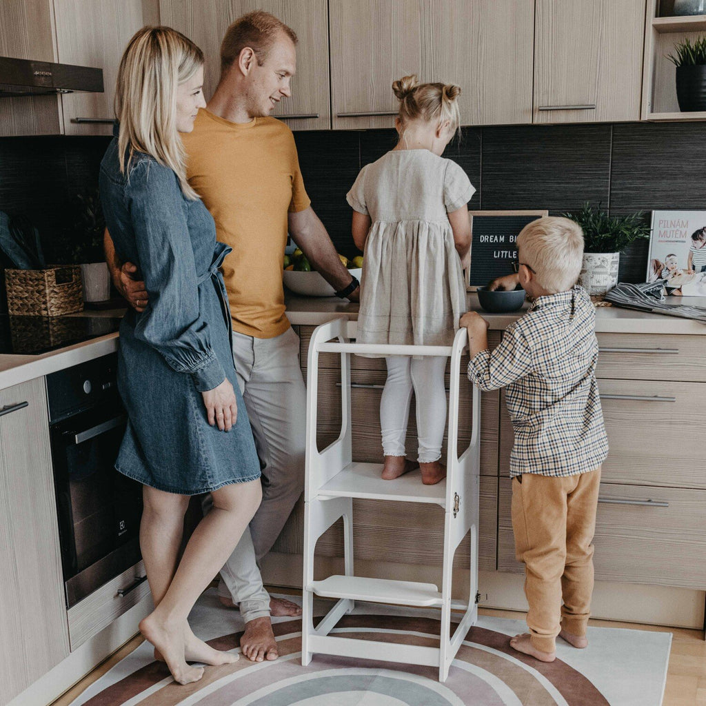 3. Family with two children using white kitchen tower in kitchen for cooking activity