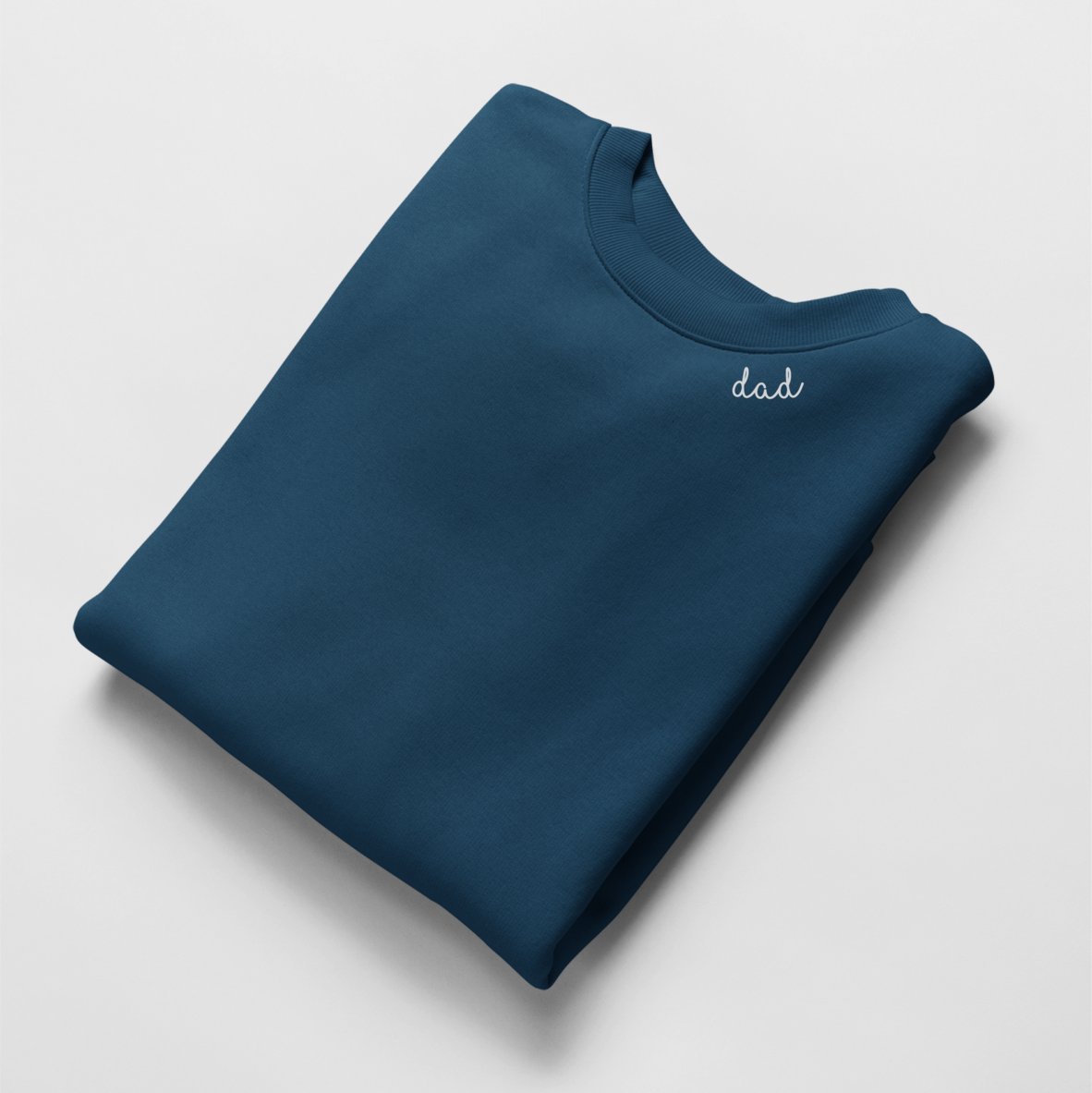 2. Navy blue unisex organic cotton sweatshirt with 'dad' embroidery, folded in studio setting