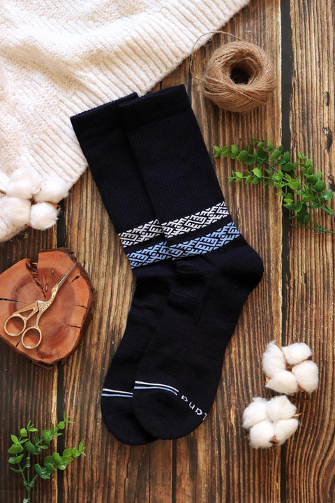 1. Lifestyle image of Baltland unisex merino wool socks in blue and white, styled on a wooden surface with cotton and greenery