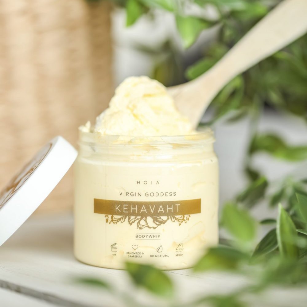 1. HOIA homespa Virgin Goddess Whipped Body Butter in open jar with wooden spoon, surrounded by greenery