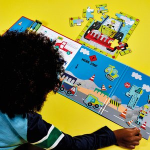 3. Child playing with Floss & Rock Magnetic Multiplay Scene on yellow background, assembling puzzle pieces on construction site theme