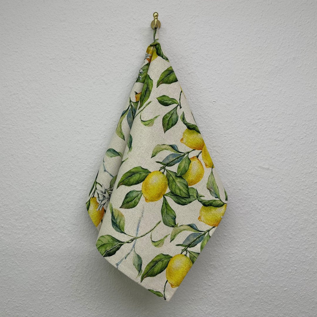 1. Hortensias Home Lemon Linen Kitchen Towel hanging on wall, showcasing vibrant lemon print and cotton-linen blend