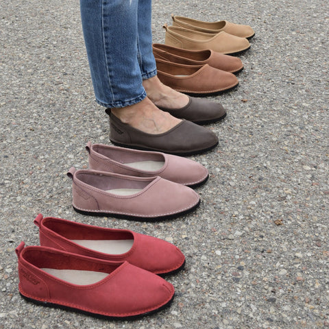 5. Lineup of OmaKing Kuutsid shoes in different colors, including dark red, worn by a person in jeans, outdoor setting