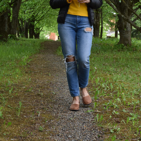 1. Woman walking on a forest path wearing Omaking Kuutsid brown leather shoes with jeans