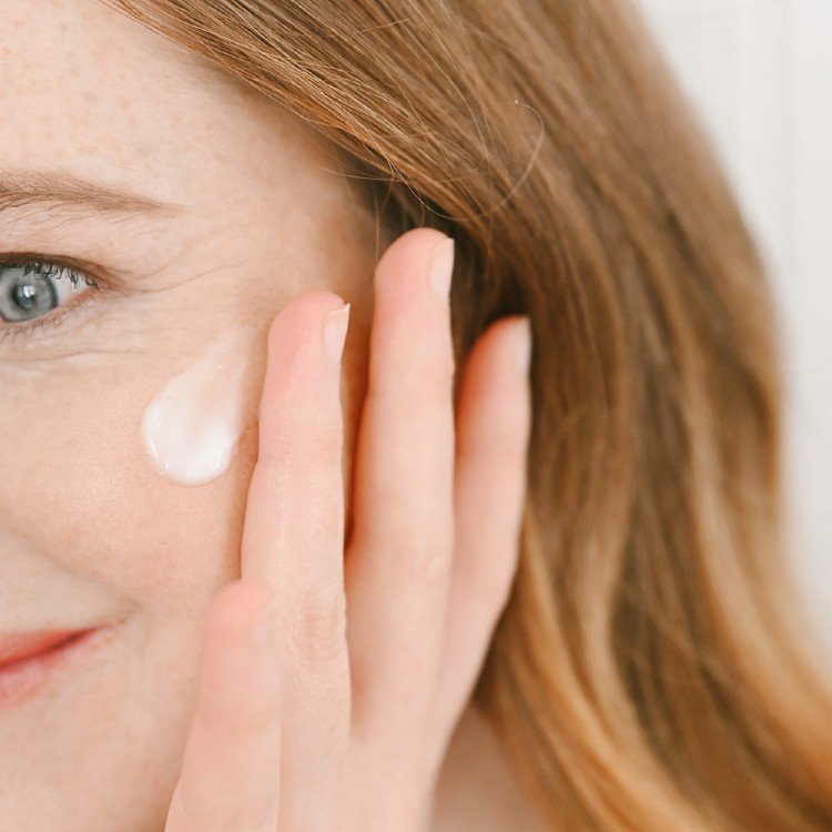 1. Woman applying Vegan Fox nourishing face cream to her cheek, highlighting skincare routine