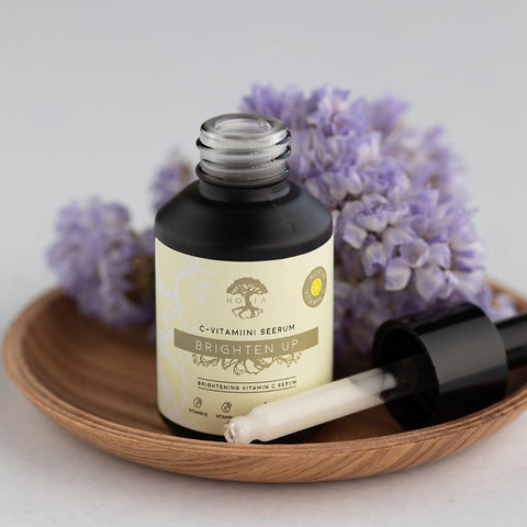 2. Open HOIA homespa Brightening Vitamin C Serum bottle with dropper, shown on a wooden tray with purple flowers